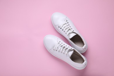 Photo of Pair of stylish white sneakers on pink background, top view. Space for text