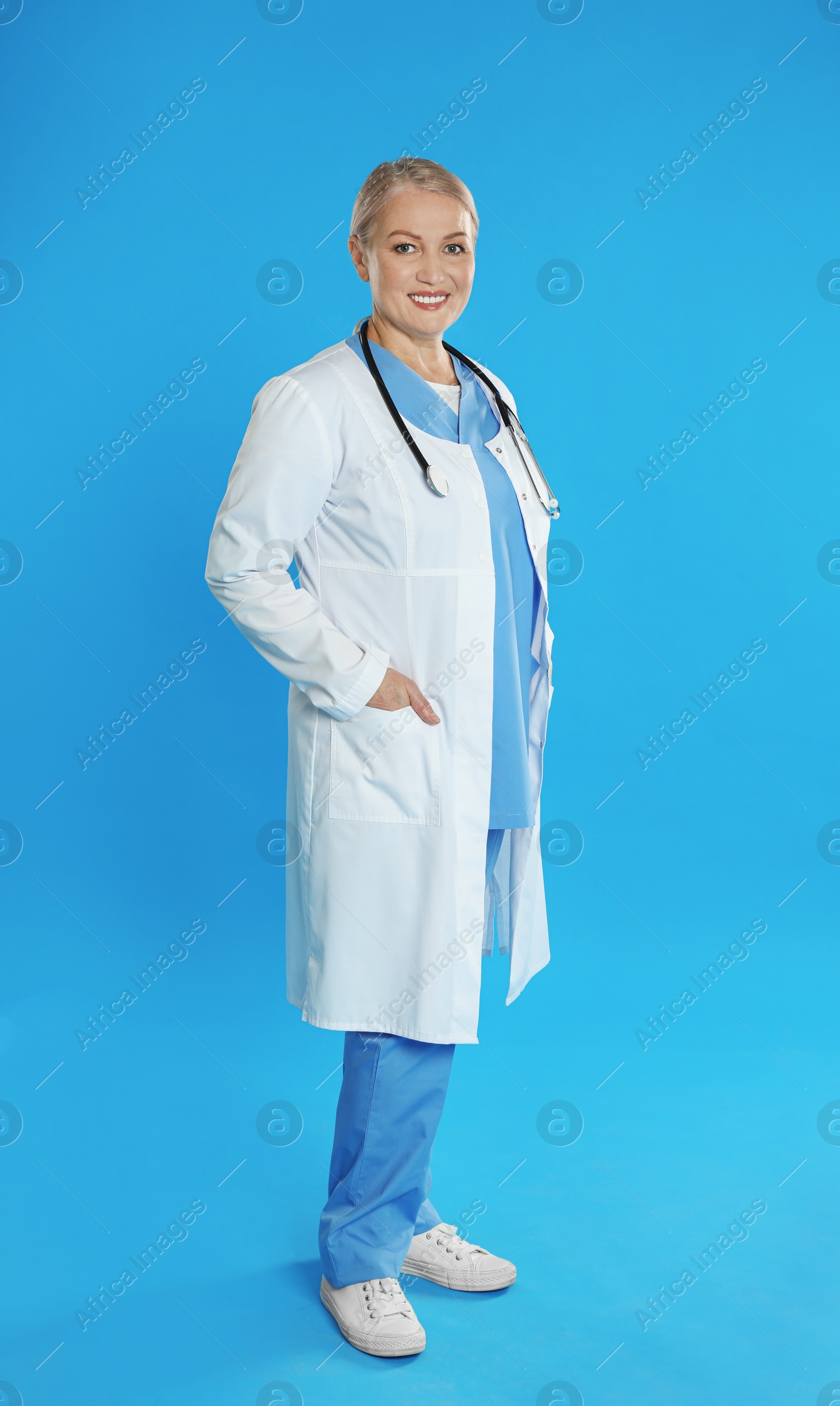 Photo of Portrait of mature doctor with stethoscope on blue background