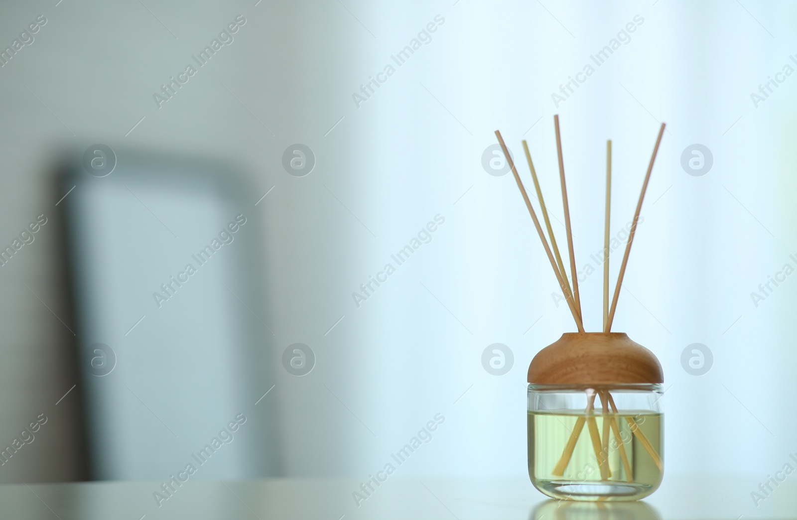 Photo of Aromatic reed air freshener on table indoors. Space for text