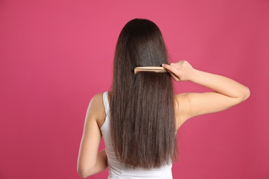 Back view of young woman with hair comb on color background