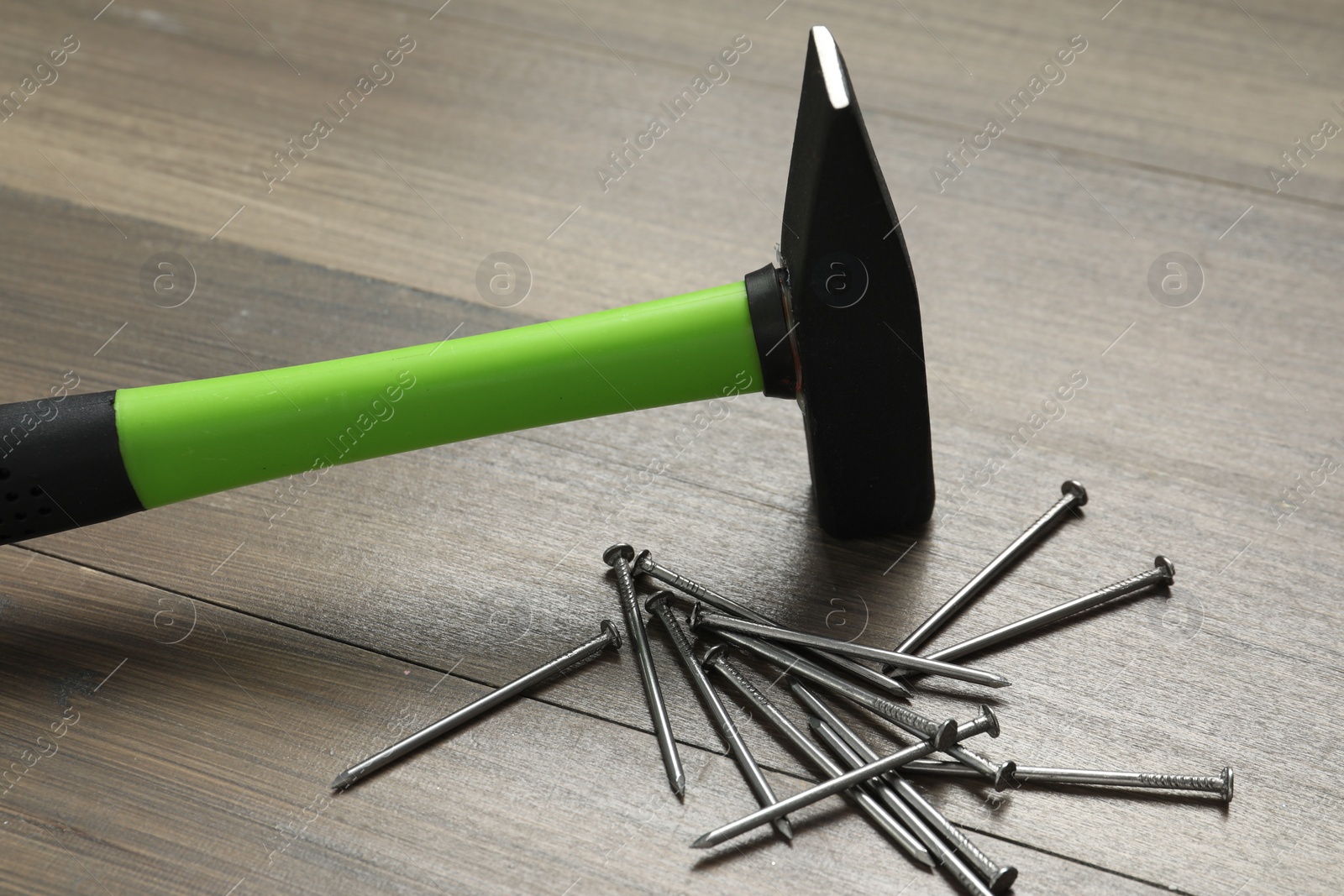 Photo of New hammer and metal nails on wooden table. Professional construction tool