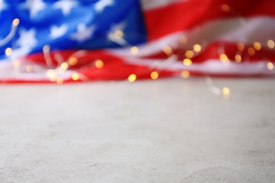 Photo of Blurred American flag and garland on grey table. Space for text
