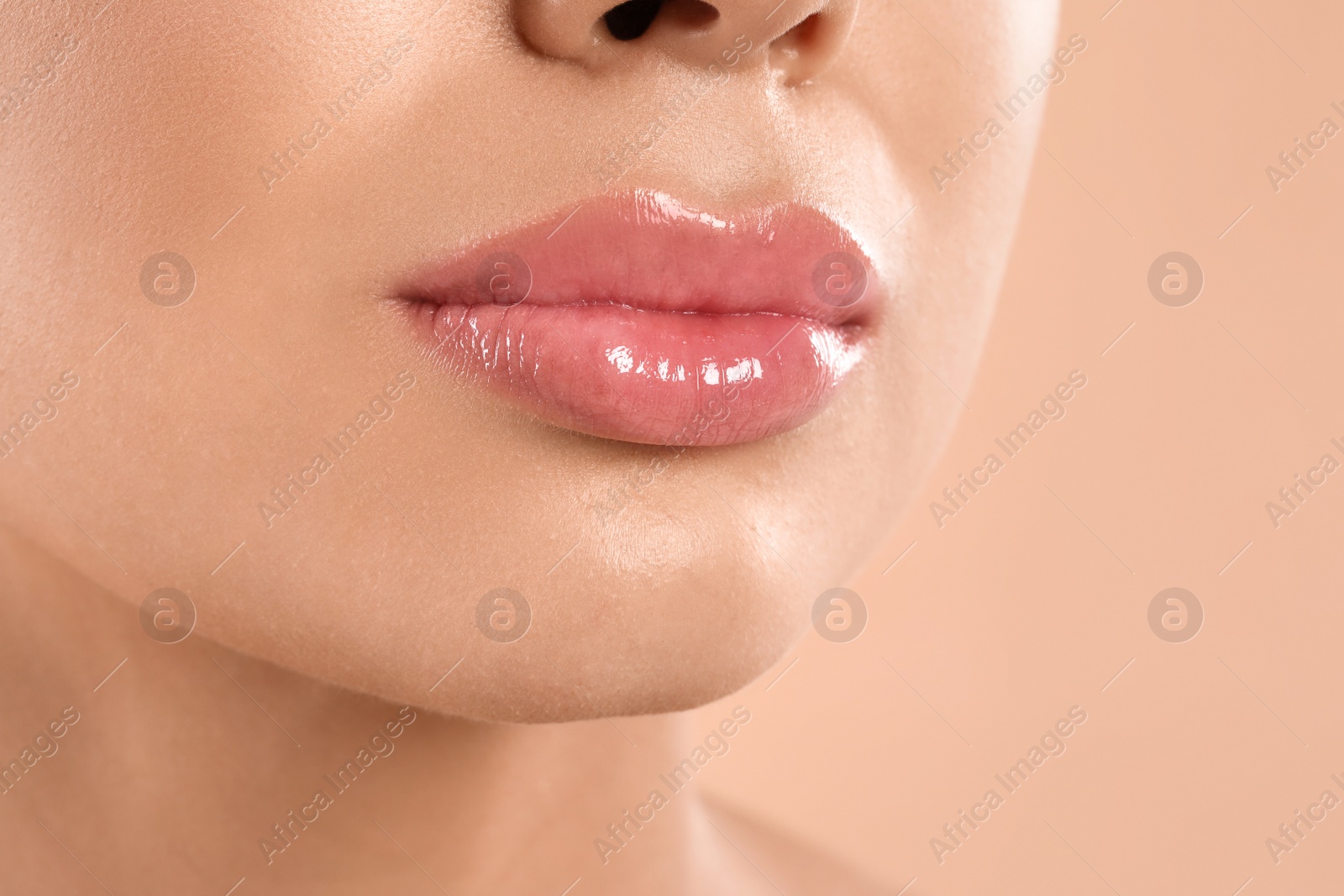 Photo of Young woman with beautiful full lips on peach background, closeup