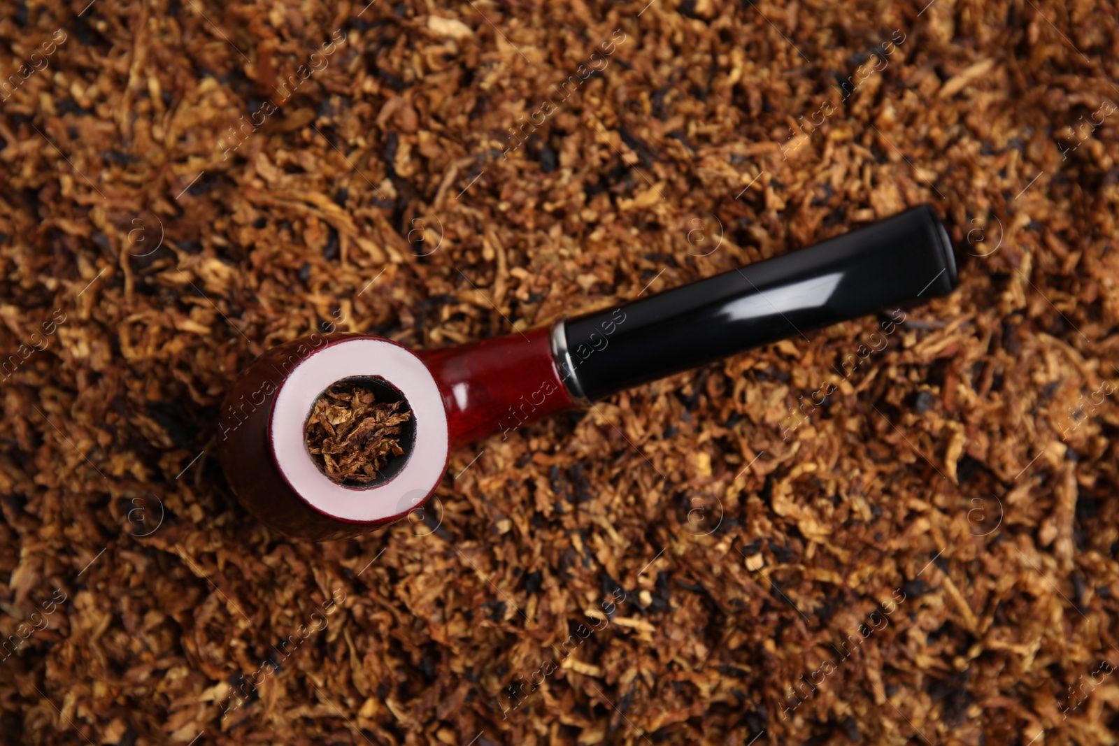 Photo of Smoking pipe on pile of tobacco, top view