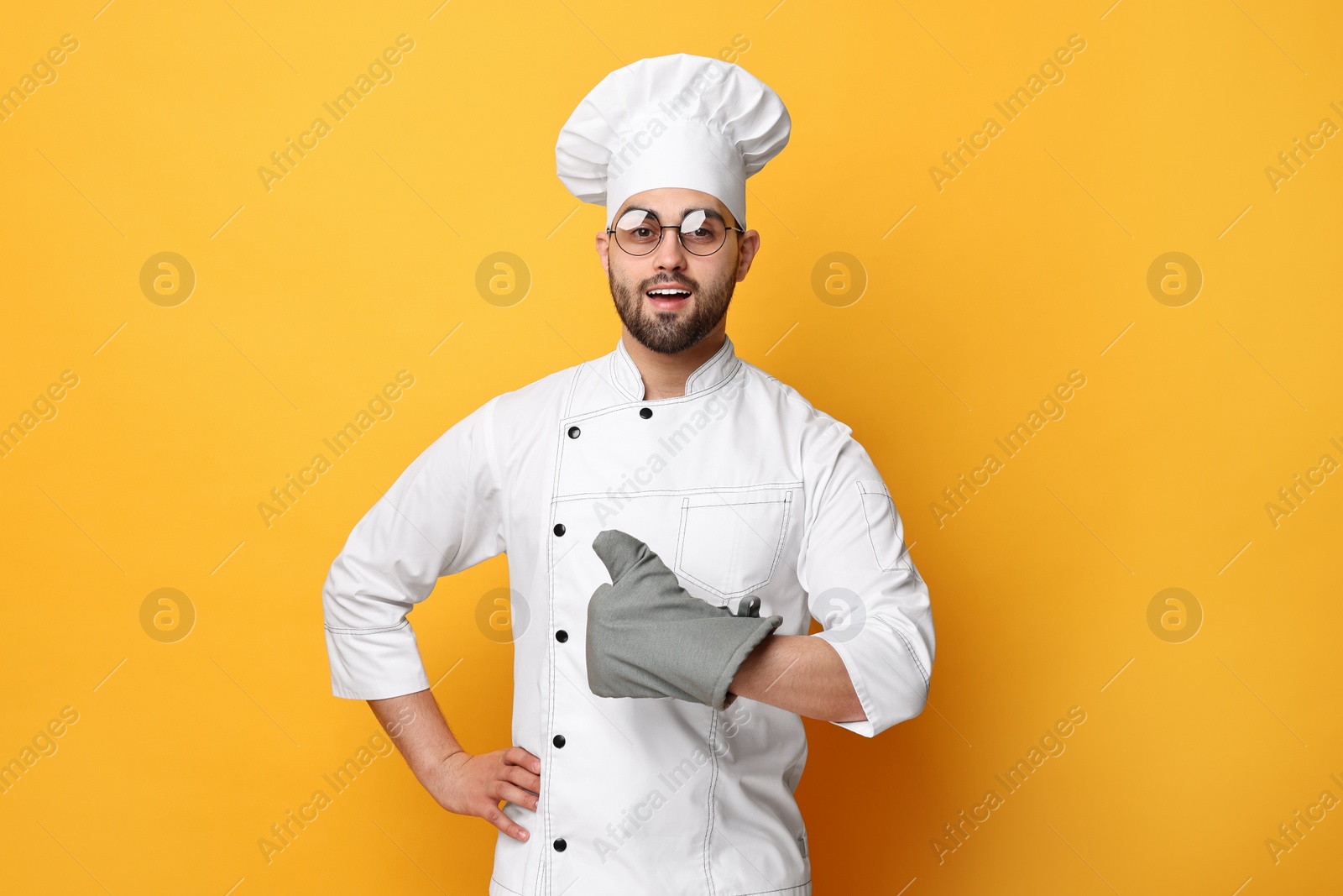 Photo of Professional chef showing thumb up on yellow background