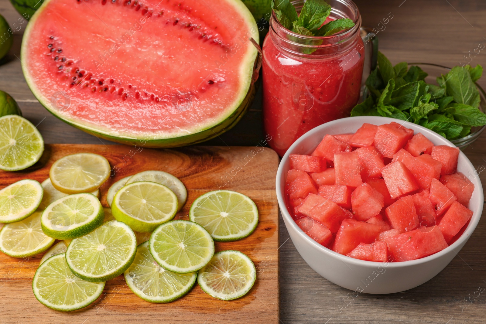 Photo of Tasty watermelon drink with lime and fresh ingredients on wooden table