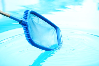 Photo of Cleaning outdoor pool with scoop net, closeup