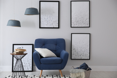 Photo of Beautiful artworks and comfortable armchair in stylish room. Interior design