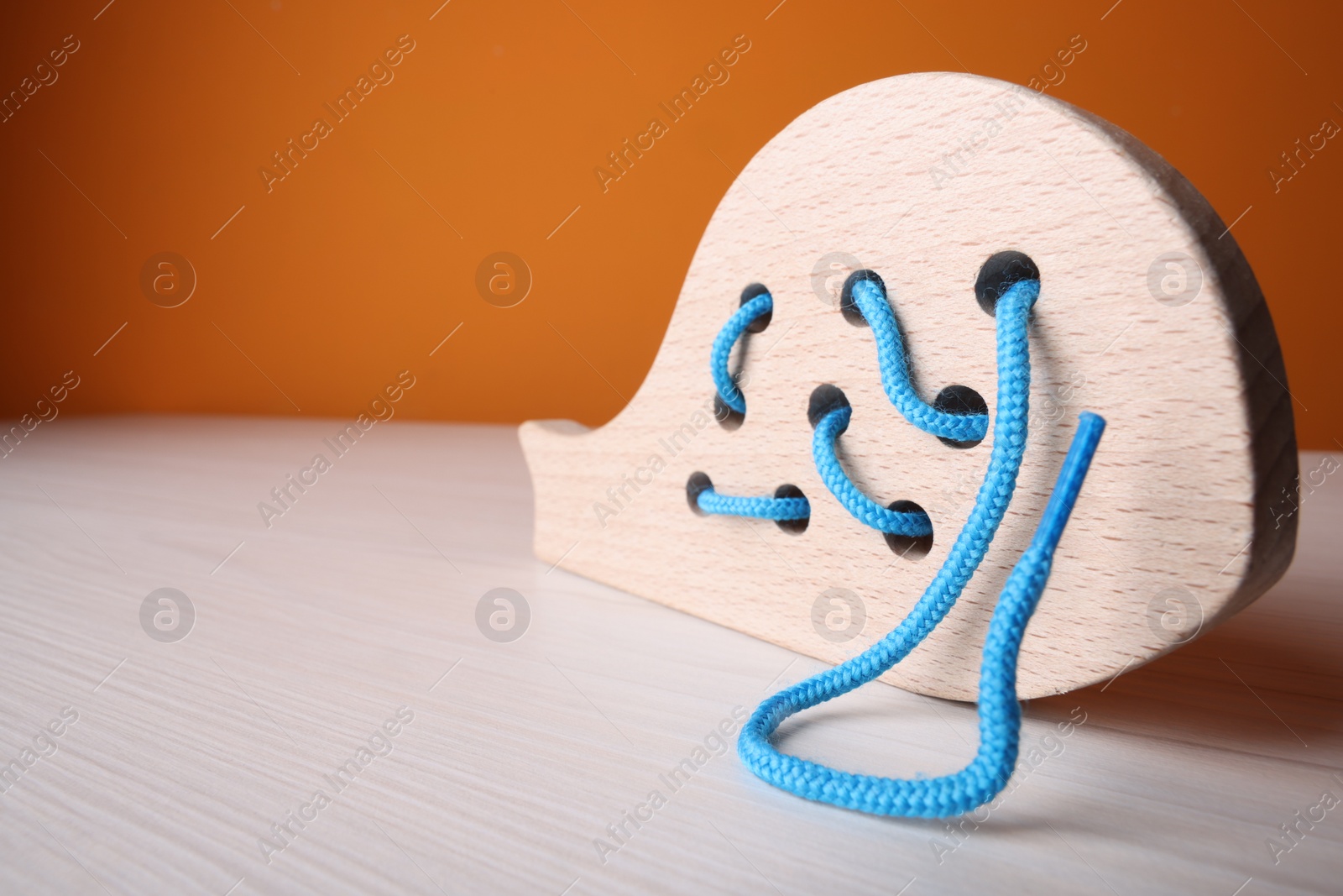 Photo of Wooden lacing toy on light table, closeup and space for text. Motor skills development