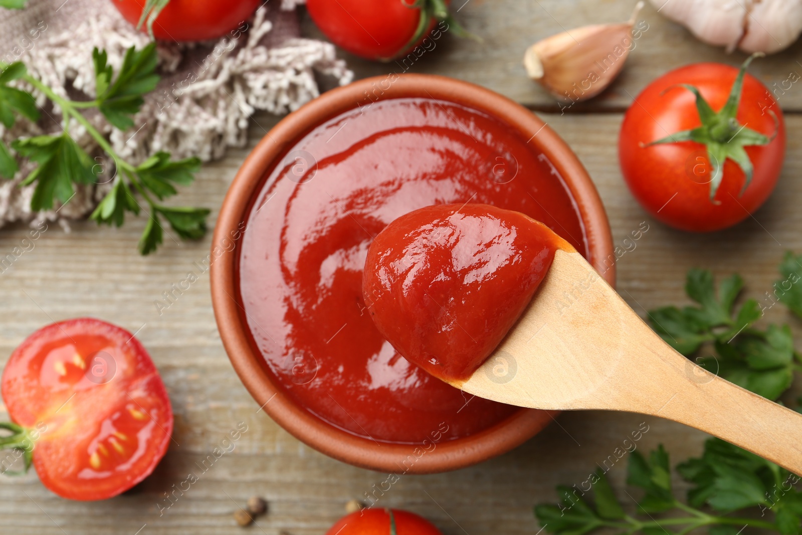 Photo of Tasty ketchup, fresh tomatoes, parsley and spices on wooden table, flat lay