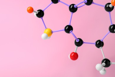 Structure of molecule on pink background, closeup and space for text. Chemical model