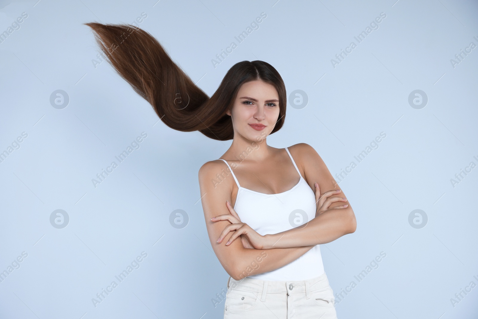 Photo of Young woman with strong healthy hair on light blue background