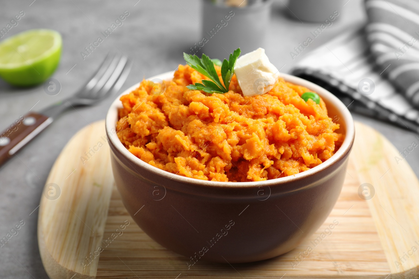 Photo of Board with bowl of tasty sweet potato puree on grey table