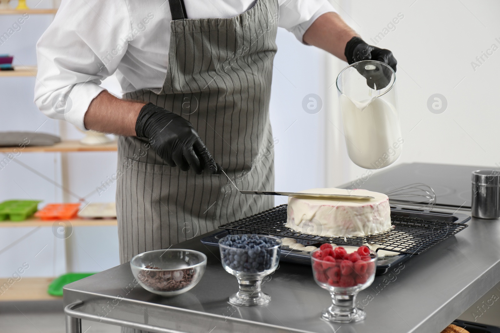 Photo of Male pastry chef preparing cake at table in kitchen, closeup