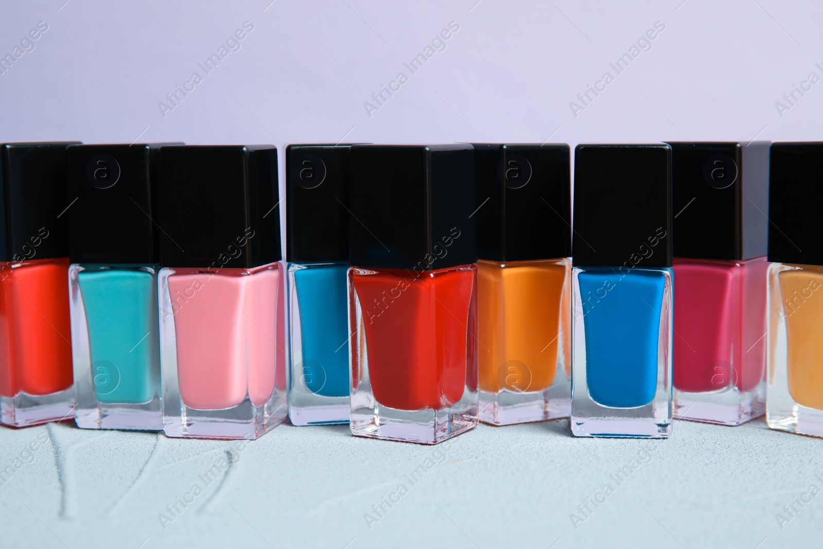 Photo of Bright nail polishes on table against color background