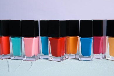 Photo of Bright nail polishes on table against color background