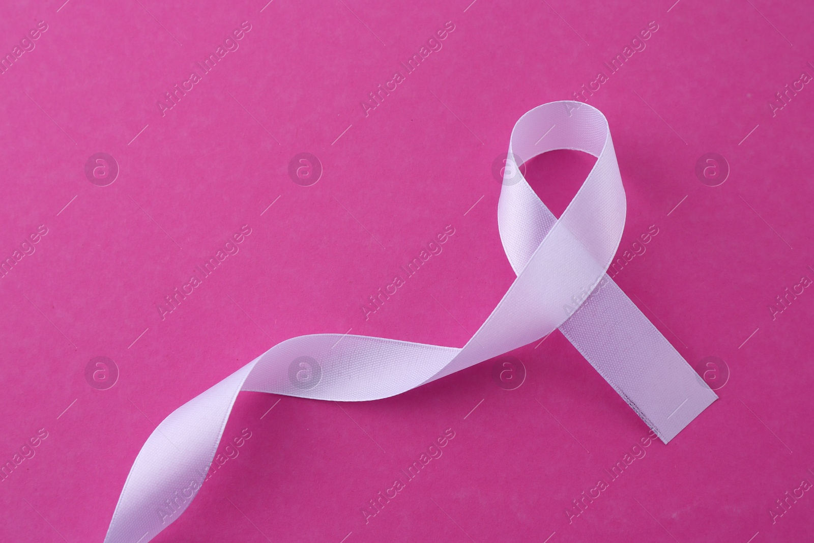 Photo of White awareness ribbon on pink background, top view