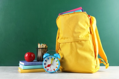 Photo of Backpack with school stationery on table against blackboard