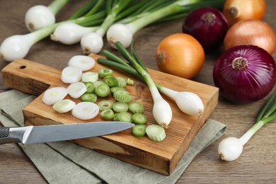 Photo of Different kinds of onions on wooden table, closeup