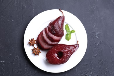 Tasty red wine poached pears, mint and anise on black table, top view