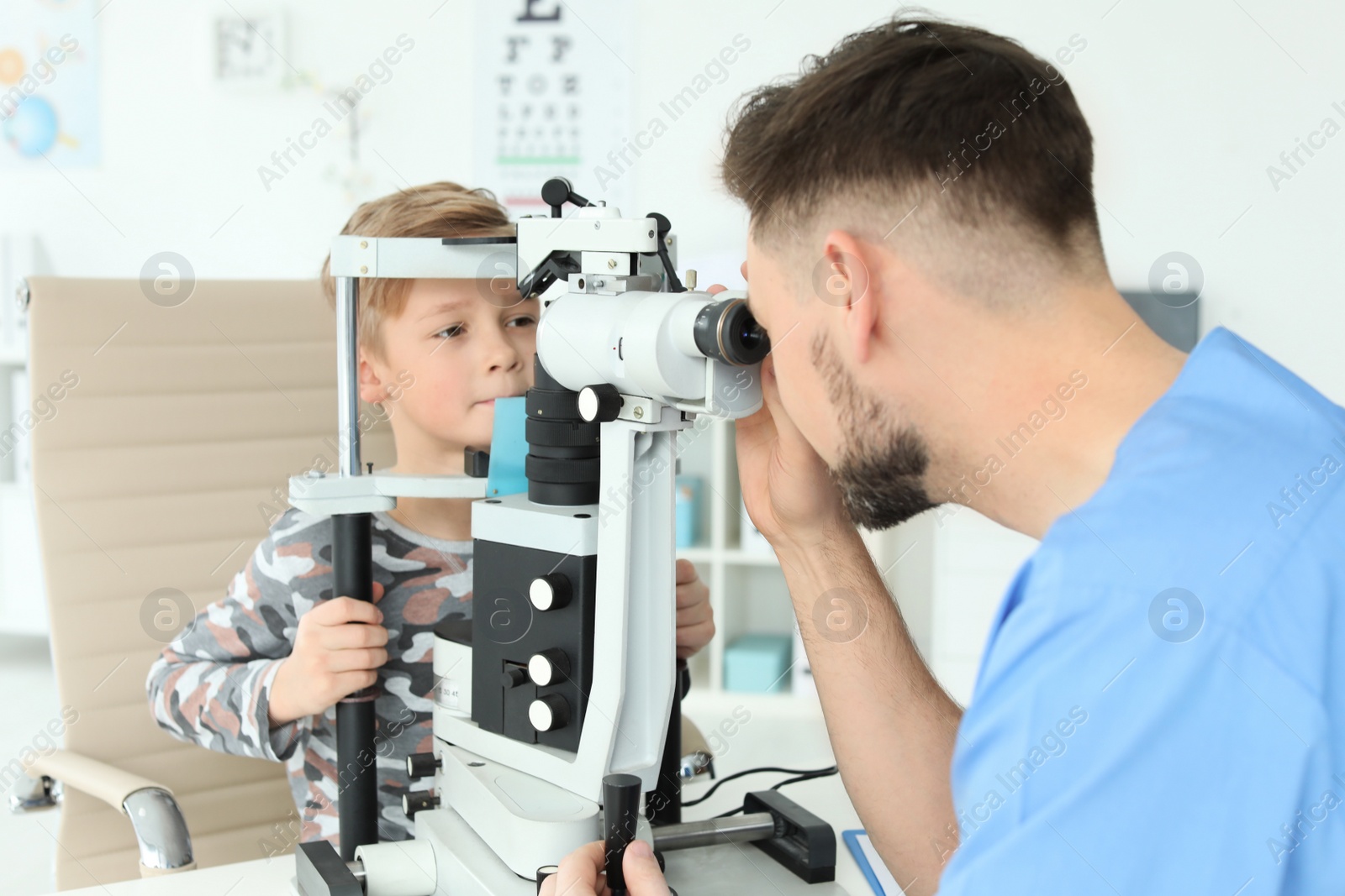 Photo of Ophthalmologist examining little boy in clinic