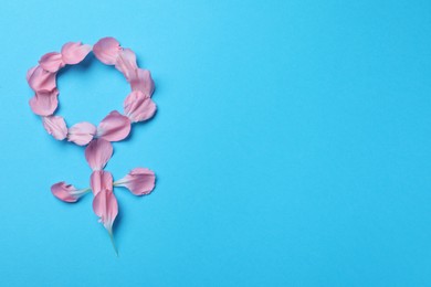 Female gender sign made of petals on light blue background, top view and space for text. Women's health concept