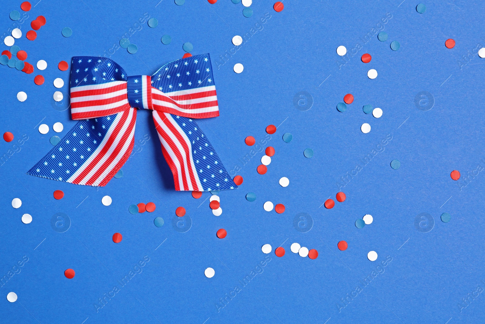 Photo of Ribbon bow and confetti on color background, flat lay with space for text. USA Independence Day