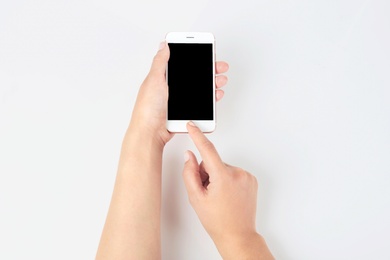Photo of Young woman holding mobile phone with blank screen in hand on white background