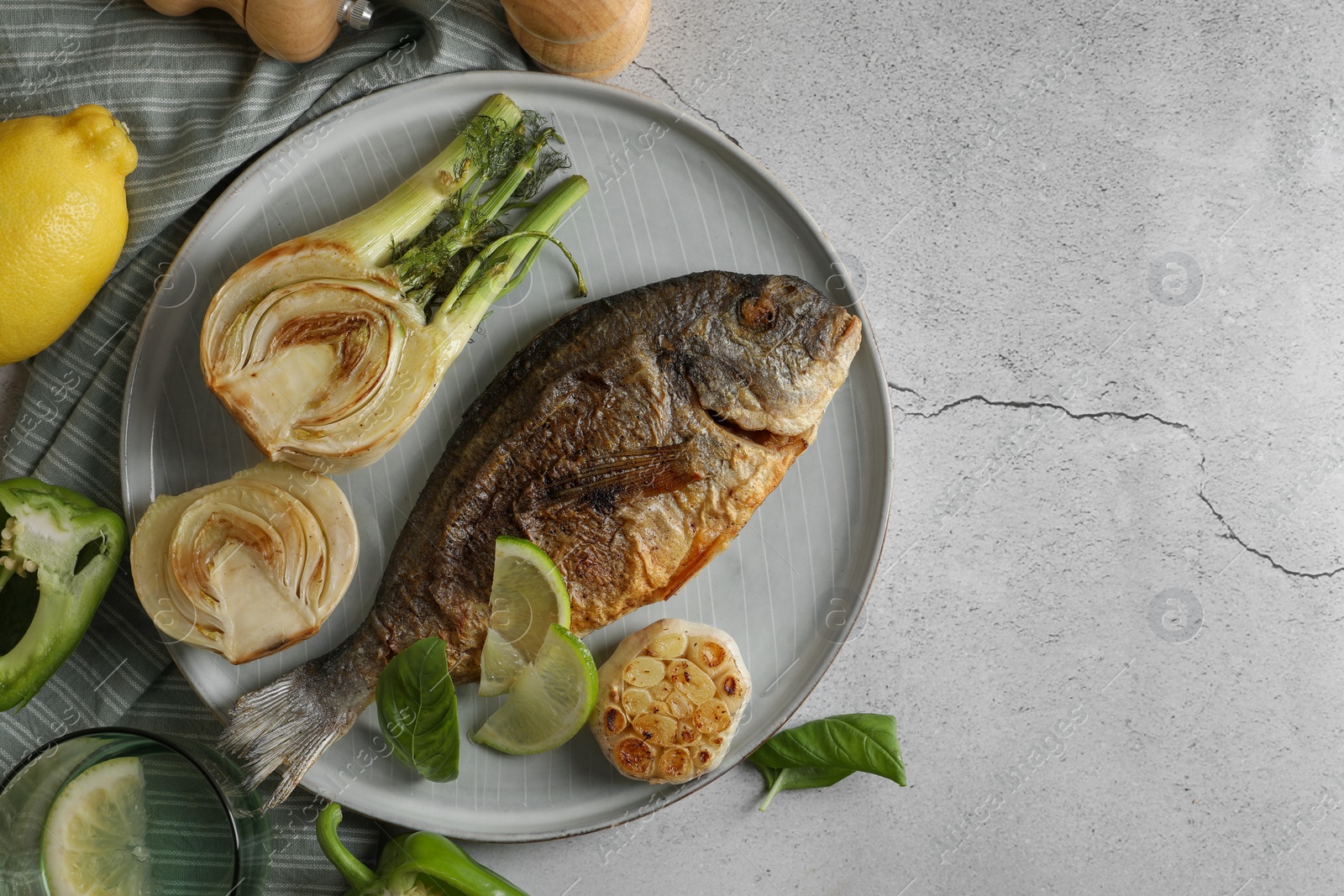 Photo of Delicious dorado fish with vegetables served on light grey table, flat lay. Space for text