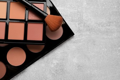 Photo of Contouring palettes and brush on light gray background, flat lay with space for text. Professional cosmetic product