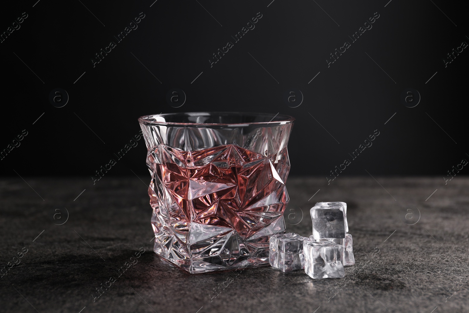 Photo of Energy drink in glass and ice cubes on grey table