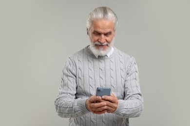 Photo of Senior man using smartphone on light grey background