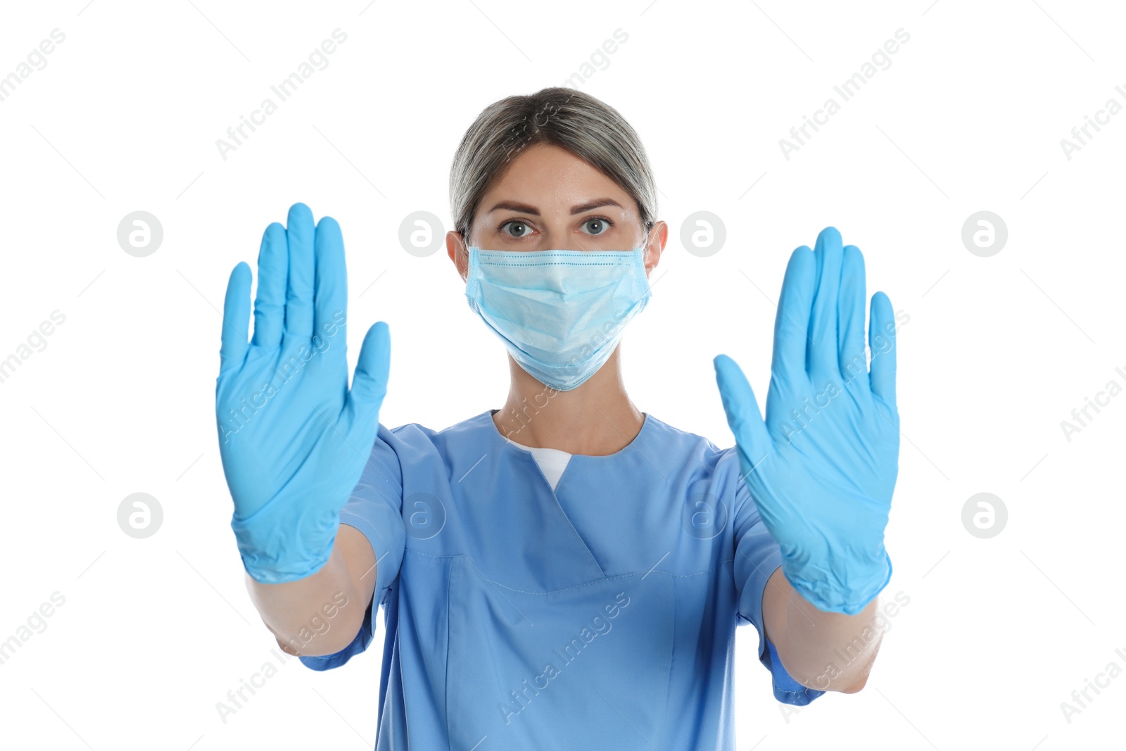 Photo of Doctor in protective mask showing stop gesture on white background. Prevent spreading of coronavirus