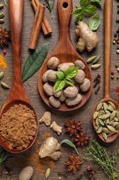 Photo of Different herbs and spices with spoons on wooden table, flat lay