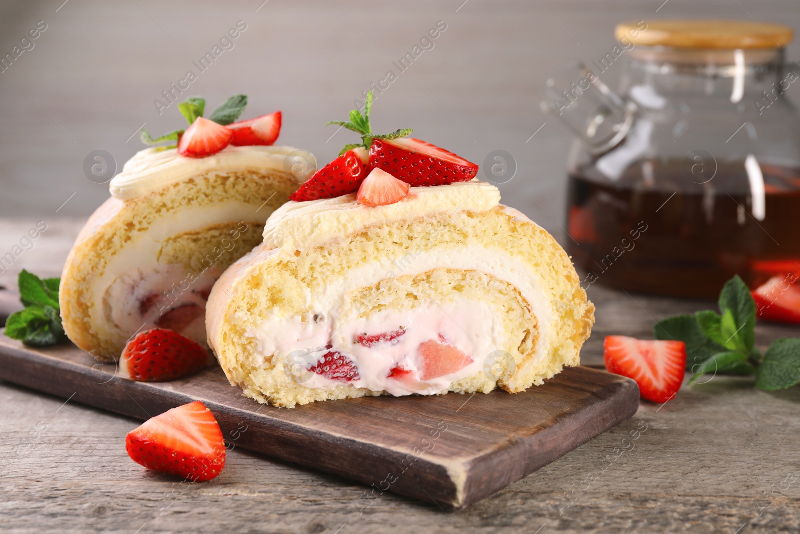 Photo of Pieces of delicious cake roll with strawberries and cream on wooden table, closeup