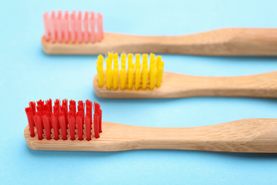 Photo of Toothbrushes made of bamboo on light blue background, closeup