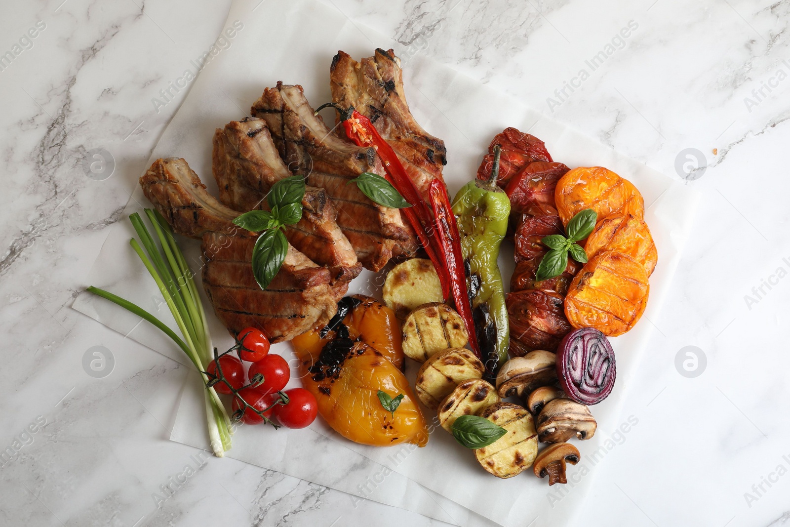 Photo of Delicious grilled meat and vegetables on white marble table, top view