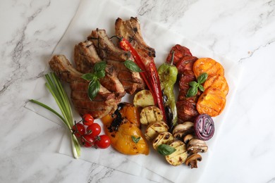 Photo of Delicious grilled meat and vegetables on white marble table, top view