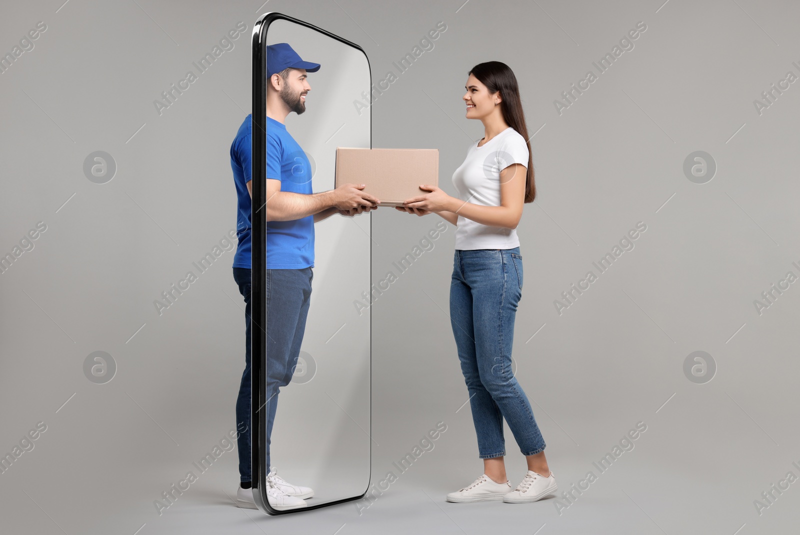 Image of Courier delivering parcel to woman through huge smartphone on grey background