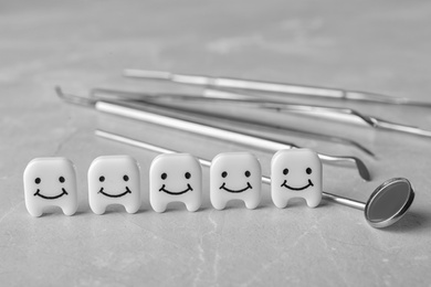 Decorative teeth and dentist tools on grey table, closeup. Space for text