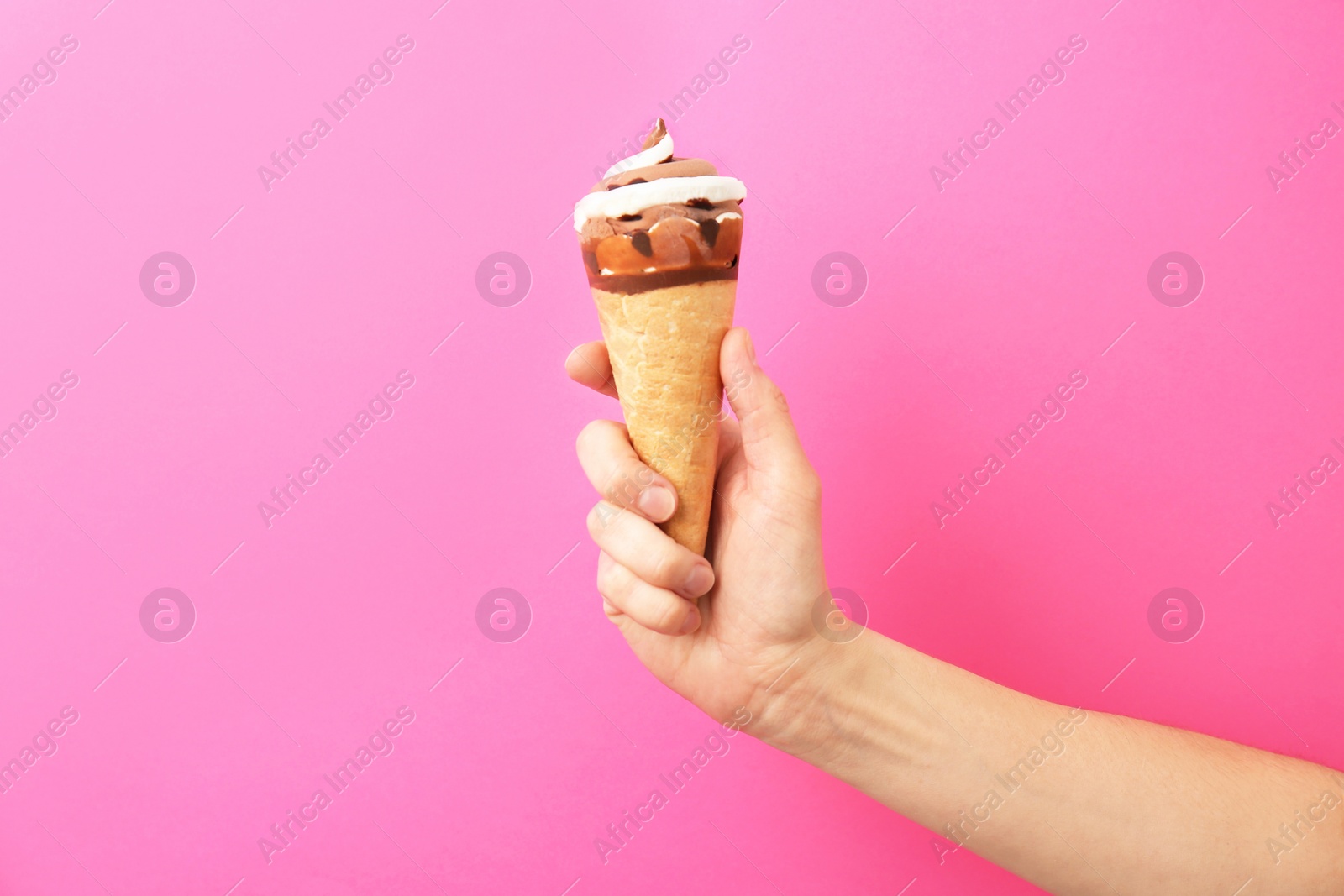 Photo of Woman holding yummy ice cream on color background. Focus on hand