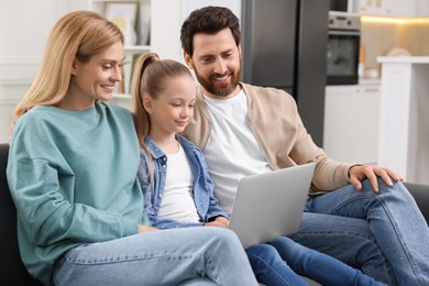 Happy family spending time together and using laptop on sofa at home