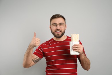 Photo of Young man with delicious shawarma on grey background