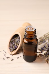 Photo of Bottle of essential oil and lavender flowers on white wooden table, closeup