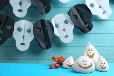 Image of White pumpkin shaped candle holders and jelly candies on light blue table. Halloween decoration