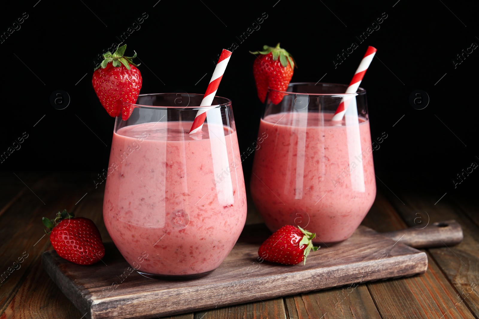 Photo of Tasty strawberry smoothies in glasses on wooden board