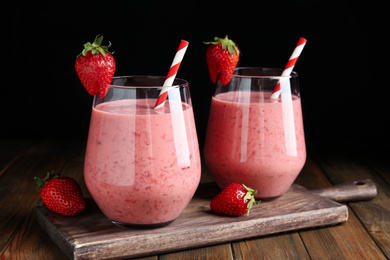 Tasty strawberry smoothies in glasses on wooden board