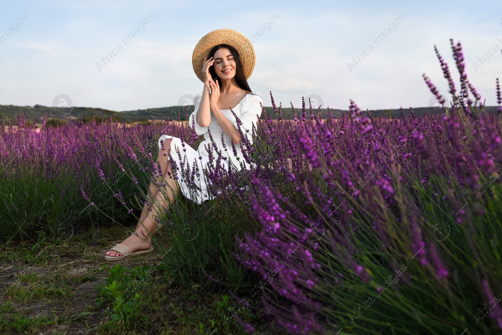 Photo of Beautiful young woman sitting in lavender field