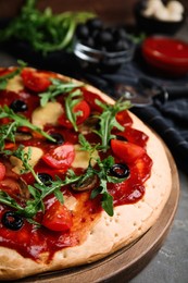 Pita pizza with cheese, olives, tomatoes and arugula on grey table, closeup