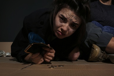 Poor woman with empty wallet and coins indoors